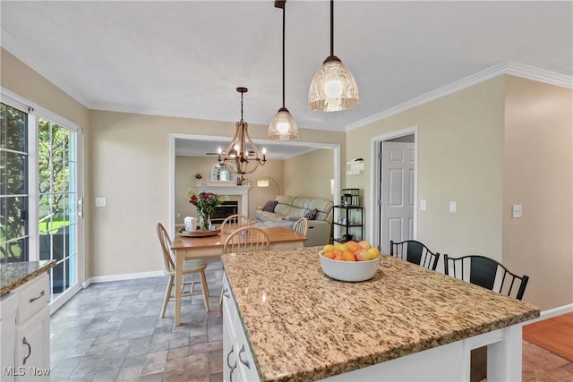 dining space with baseboards, a chandelier, ornamental molding, and light stone finish flooring