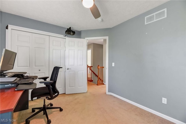 office area featuring a ceiling fan, light carpet, baseboards, and a textured ceiling