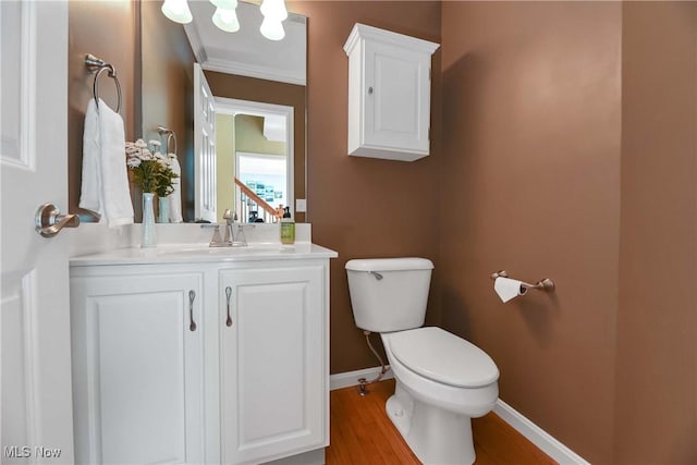 bathroom with toilet, baseboards, vanity, and wood finished floors