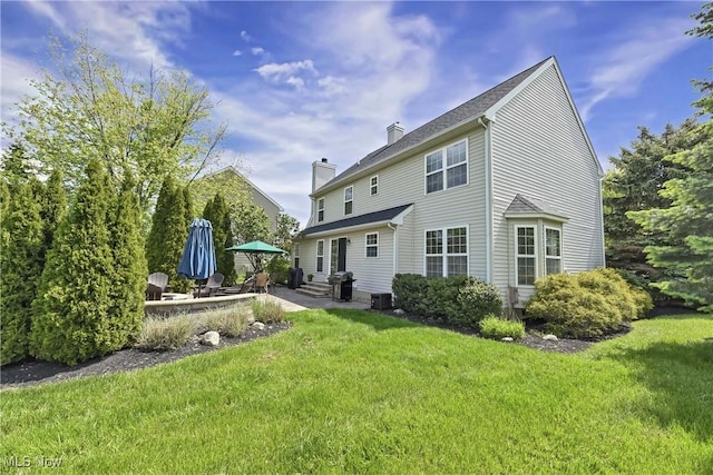 back of property featuring a chimney, a patio, a lawn, entry steps, and central AC
