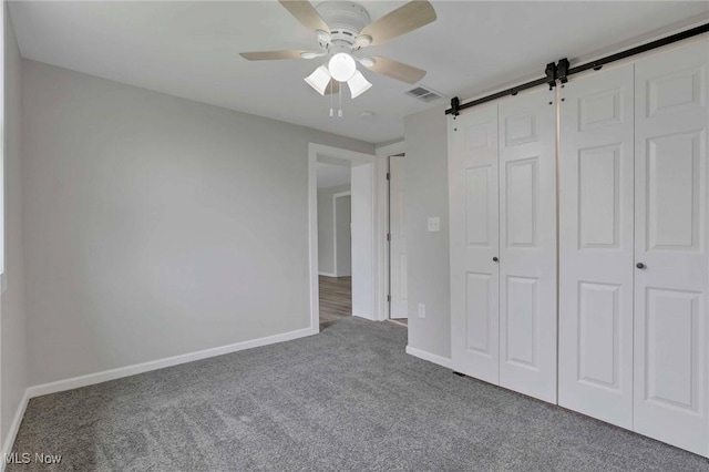 35 W 5th St, Dresden, OH 43821 - unfurnished bedroom featuring carpet flooring, a barn door, baseboards, and a closet