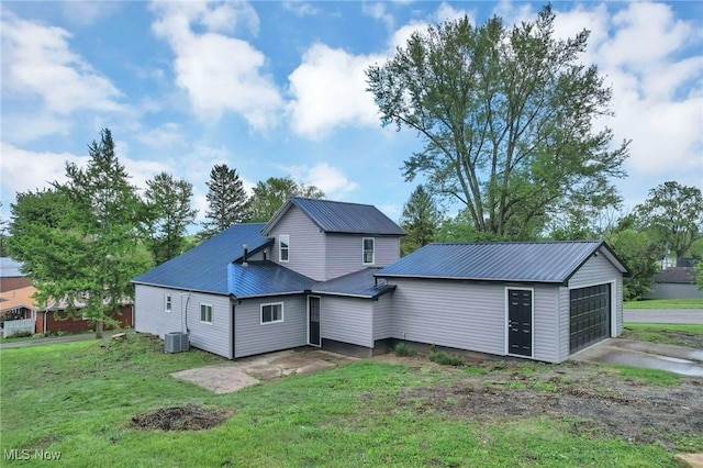 35 W 5th St, Dresden, OH 43821 - rear view of house with central AC, metal roof, a lawn, a garage, and an outbuilding