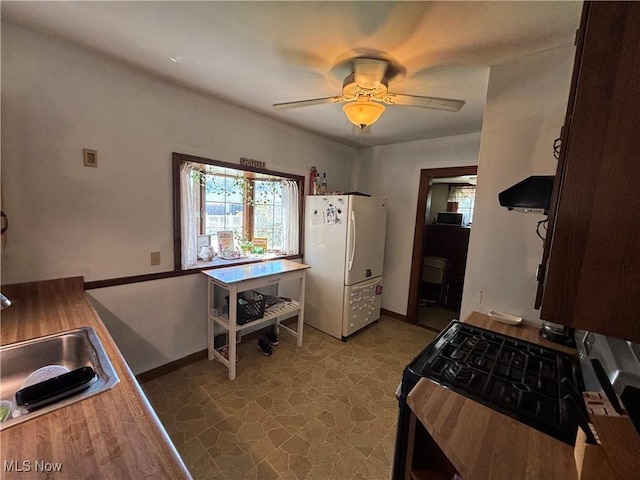 4212 W 48th St, Cleveland, OH 44144 - kitchen with freestanding refrigerator, a sink, baseboards, a ceiling fan, and exhaust hood