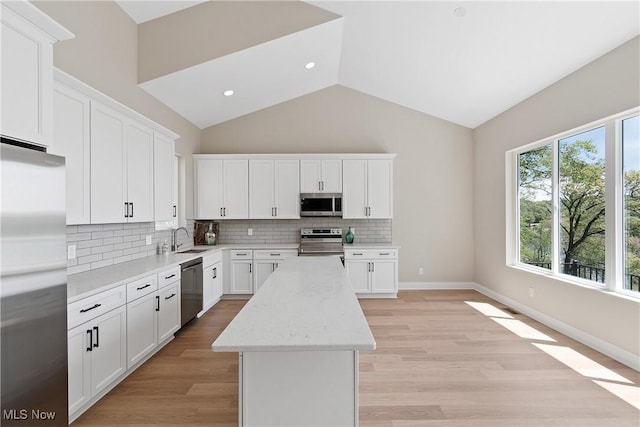 26 Oneida Trl, Malvern, OH 44644 - kitchen with stainless steel appliances, a sink, a center island, vaulted ceiling, and decorative backsplash