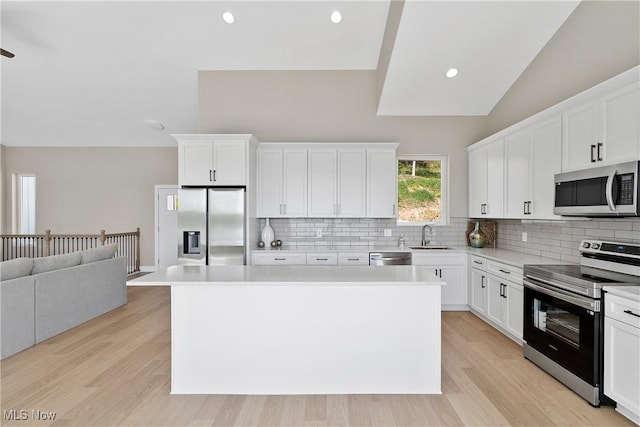 26 Oneida Trl, Malvern, OH 44644 - kitchen with stainless steel appliances, vaulted ceiling, decorative backsplash, a kitchen island, and open floor plan