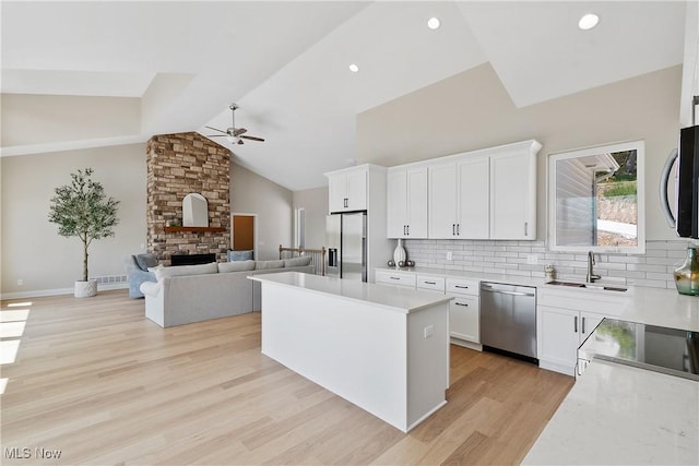 26 Oneida Trl, Malvern, OH 44644 - kitchen with stainless steel appliances, ceiling fan, a fireplace, open floor plan, and tasteful backsplash