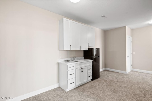 26 Oneida Trl, Malvern, OH 44644 - kitchen featuring freestanding refrigerator, light countertops, white cabinetry, and light colored carpet