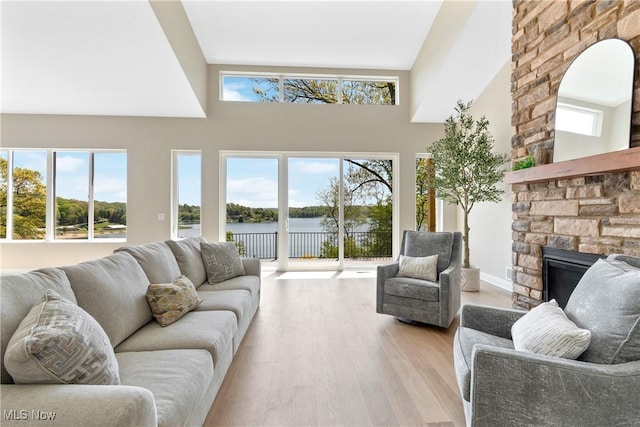 26 Oneida Trl, Malvern, OH 44644 - living area featuring a fireplace, a towering ceiling, a water view, and wood finished floors