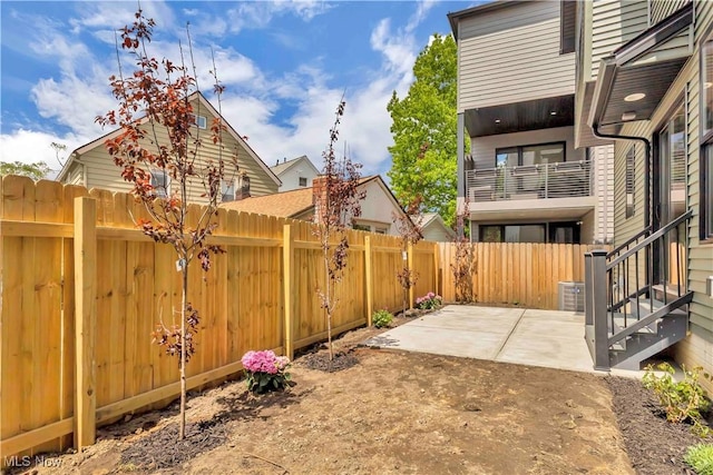 view of patio featuring a fenced backyard, central AC unit, and a balcony