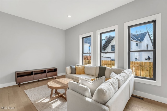 living area featuring healthy amount of natural light, baseboards, light wood-type flooring, and recessed lighting