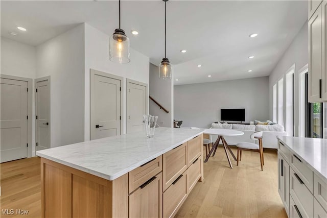 kitchen featuring light wood-style floors, recessed lighting, light stone counters, hanging light fixtures, and a kitchen island