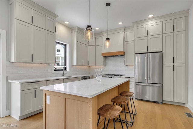 kitchen with high quality fridge, a sink, decorative backsplash, a kitchen bar, and custom exhaust hood