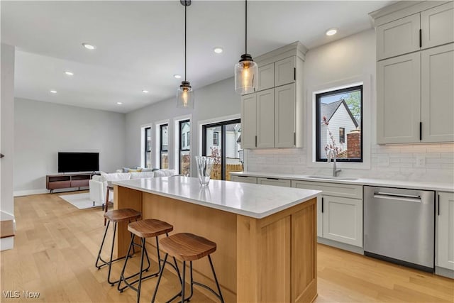 kitchen with dishwasher, a sink, tasteful backsplash, light wood-style floors, and recessed lighting