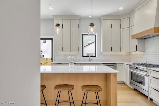 kitchen with custom range hood, a sink, stainless steel appliances, a kitchen breakfast bar, and recessed lighting