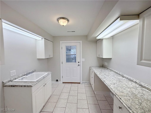 laundry room featuring a sink, baseboards, and light tile patterned flooring