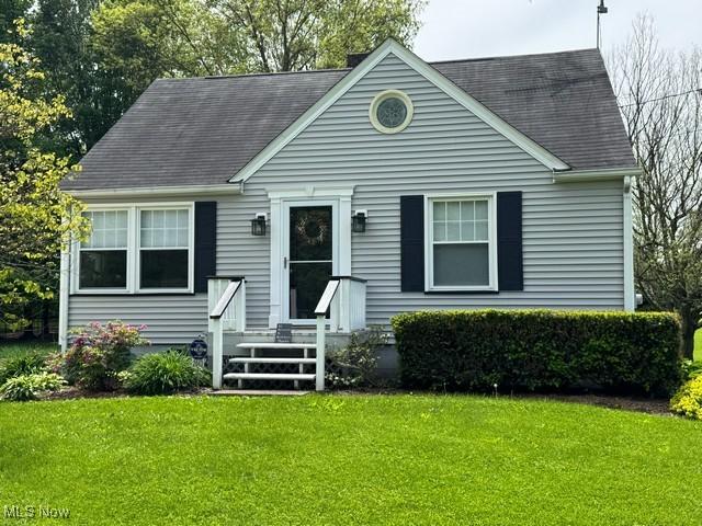 view of front of home with a front yard and roof with shingles