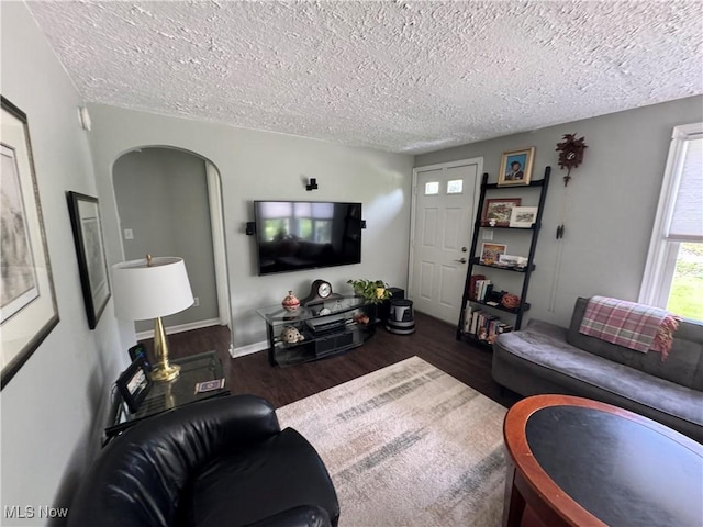 living area with wood finished floors, a textured ceiling, and baseboards