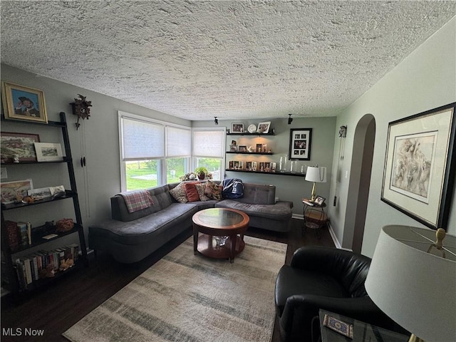 living area featuring wood finished floors, arched walkways, and a textured ceiling
