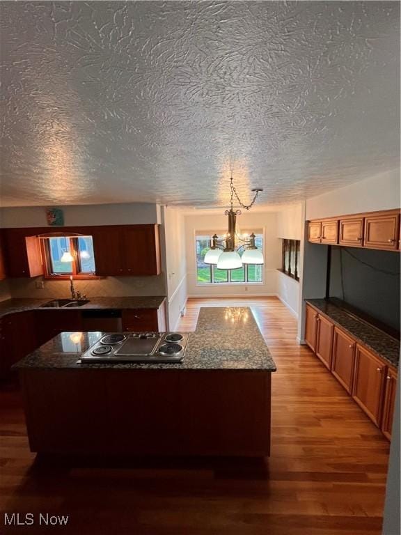 2840 Brian Dr, Parma, OH 44134 - kitchen featuring cooktop, a sink, light wood-style flooring, a textured ceiling, and a chandelier