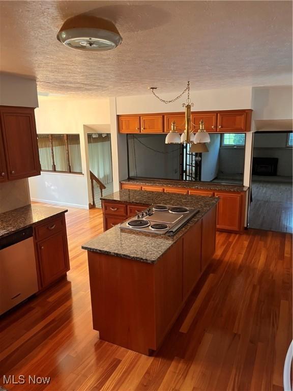 2840 Brian Dr, Parma, OH 44134 - kitchen featuring appliances with stainless steel finishes, wood finished floors, a textured ceiling, a chandelier, and dark stone counters