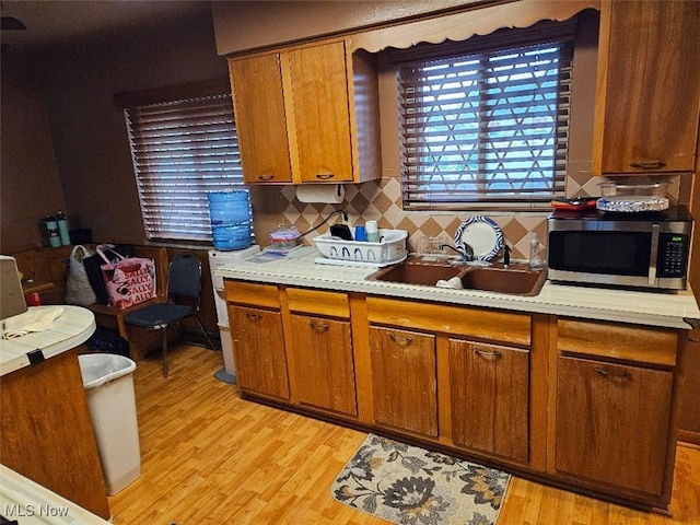 1217 Ada St, Akron, OH 44306 - kitchen with stainless steel microwave, a sink, light countertops, brown cabinets, and light wood-style flooring