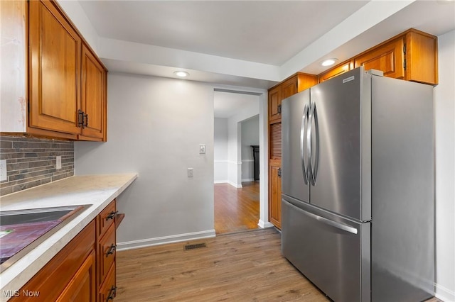 3005 Algonquin Dr, Poland, OH 44514 - kitchen featuring freestanding refrigerator, brown cabinetry, light wood-style floors, backsplash, and baseboards