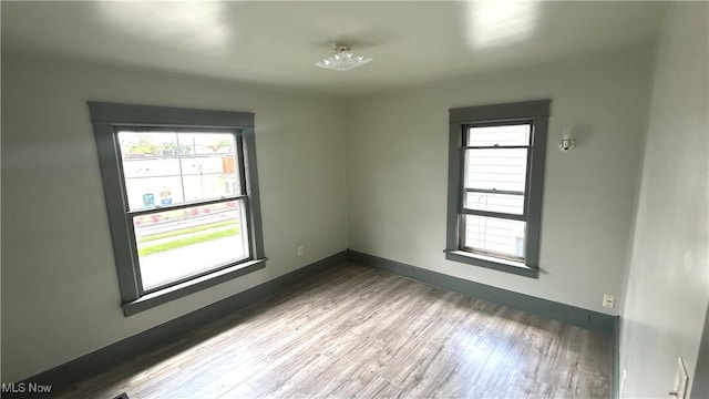 spare room with plenty of natural light, wood finished floors, and baseboards