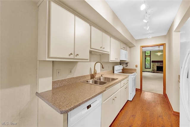 33 Brandon Pl, Rocky River, OH 44116 - kitchen with white appliances, a sink, wood finished floors, a fireplace with raised hearth, and white cabinetry