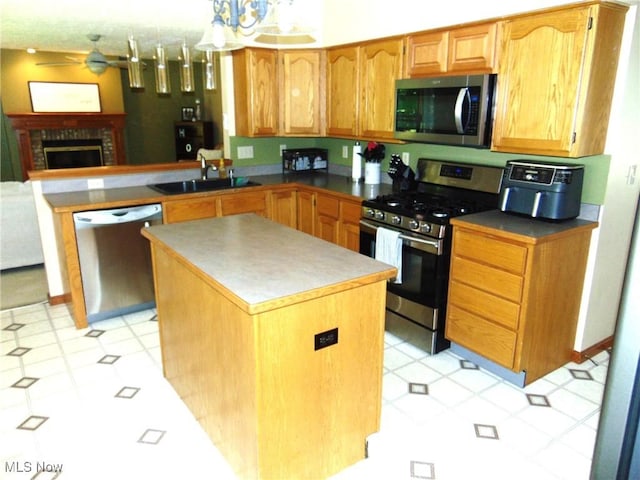 kitchen with stainless steel appliances, a sink, light flooring, ceiling fan, and a kitchen island