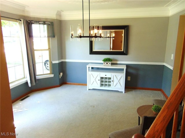 unfurnished dining area featuring crown molding, baseboards, a chandelier, and carpet flooring