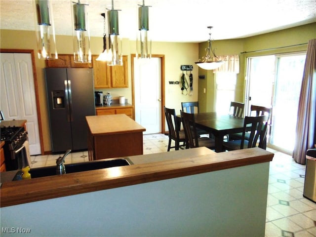 kitchen featuring fridge with ice dispenser, light flooring, a center island, and healthy amount of natural light