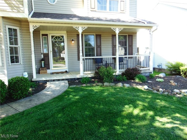 view of exterior entry featuring covered porch and a lawn
