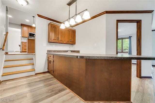 7456 Blue Ridge Dr, Mentor, OH 44060 - kitchen with stainless steel microwave, a peninsula, dark countertops, light wood-style floors, and brown cabinetry