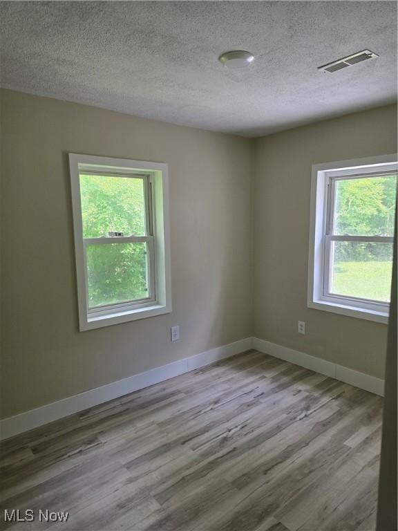 355 N Elm Ave, Tallmadge, OH 44278 - empty room with healthy amount of natural light, wood finished floors, a textured ceiling, and baseboards