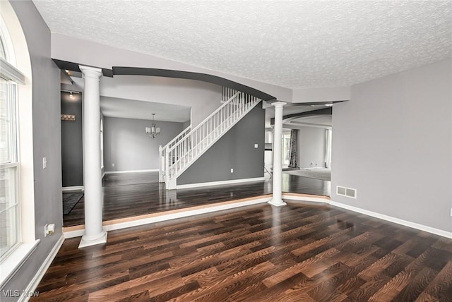 4474 Litchfield Dr, Copley, OH 44321 - unfurnished living room featuring decorative columns, wood finished floors, baseboards, a textured ceiling, and stairway