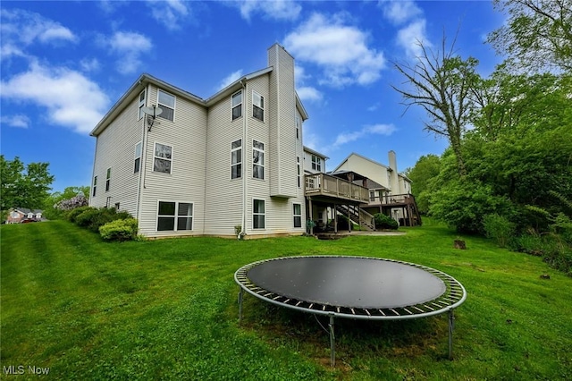 4474 Litchfield Dr, Copley, OH 44321 - rear view of property with a trampoline, a wooden deck, stairs, a chimney, and a yard