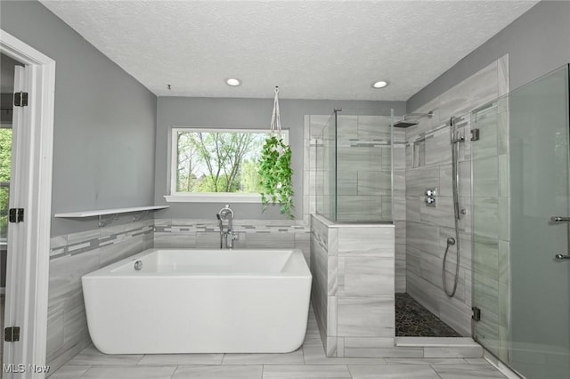 4474 Litchfield Dr, Copley, OH 44321 - full bathroom with tile walls, a stall shower, a freestanding tub, a textured ceiling, and recessed lighting