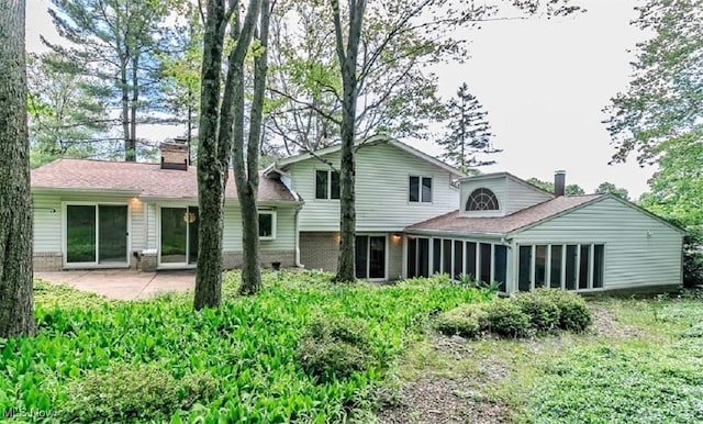 12562 Harold Dr, Chesterland, OH 44026 - rear view of property featuring a chimney, a patio, a sunroom, and brick siding
