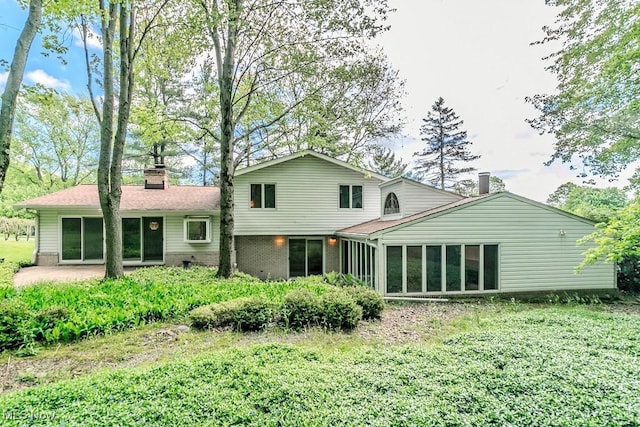 12562 Harold Dr, Chesterland, OH 44026 - rear view of house featuring a chimney, a sunroom, brick siding, and a patio area