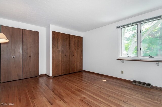 12562 Harold Dr, Chesterland, OH 44026 - unfurnished bedroom with wood finished floors, baseboards, and multiple closets