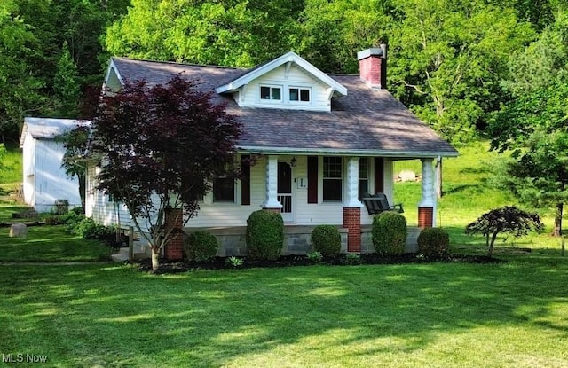 24514 County Road 24, Coshocton, OH 43812 - view of front of house with covered porch, a front yard, a chimney, and a view of trees