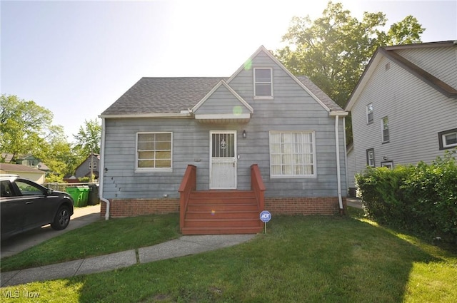 bungalow-style home with a front lawn and a shingled roof