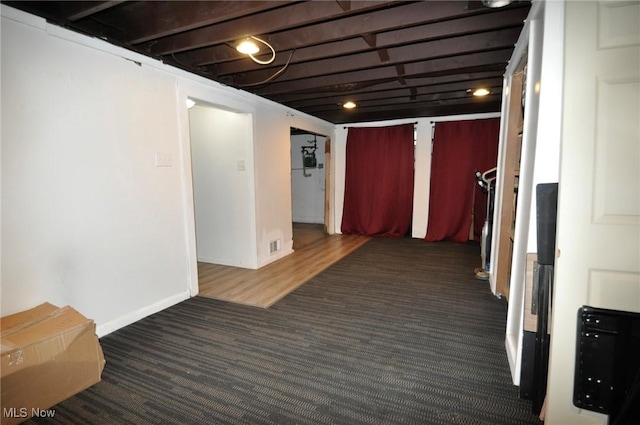 hallway featuring carpet and baseboards