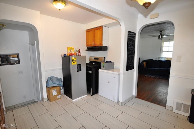 kitchen featuring stainless steel appliances, arched walkways, under cabinet range hood, and a ceiling fan
