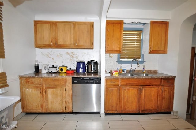 kitchen featuring dishwasher, a sink, arched walkways, and tasteful backsplash