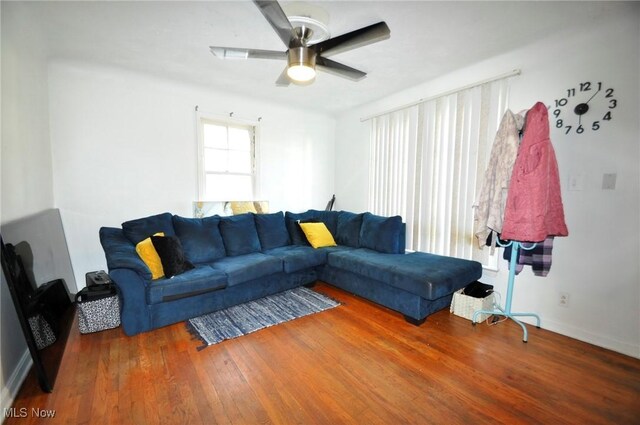 living area with wood finished floors, a ceiling fan, and baseboards
