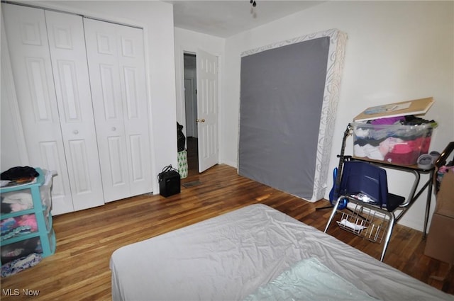 bedroom with wood finished floors and a closet
