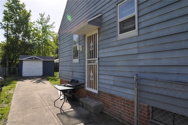 view of patio / terrace with concrete driveway, an outbuilding, a detached garage, and fence