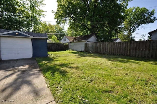 view of yard with an outdoor structure, driveway, and a detached garage