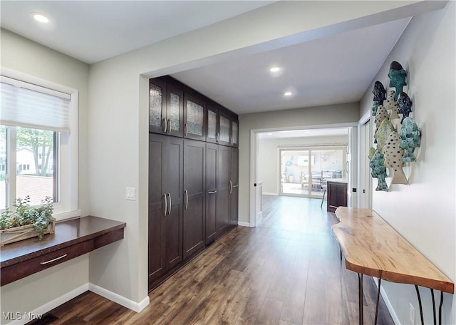 corridor with healthy amount of natural light, dark wood finished floors, recessed lighting, and baseboards